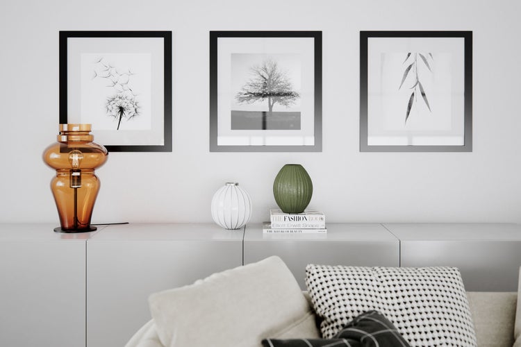 Wohnzimmer mit Kommode, Lampe, Vasen und gerahmten Bildern an der Wand.