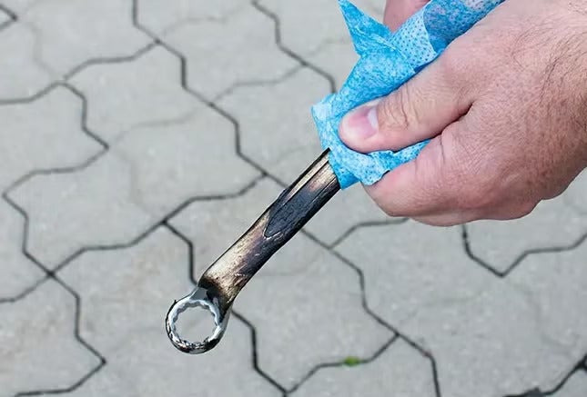 Eine Hand reinigt einen beschädigten Ringschlüssel mit einem Tuch.