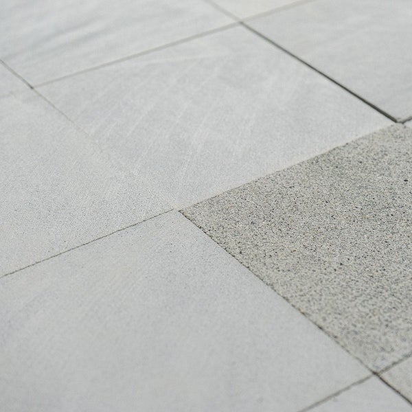 Quadratische Terrassenplatten aus Beton verlegt in einem Pflastermuster fuer den Aussenbereich