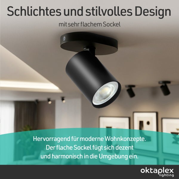 Schwarzer zylindrischer Deckenstrahler mit flachem ovalem Sockel montiert in einem hellen modernen Wohnzimmer, oktaplex lighting Logo.