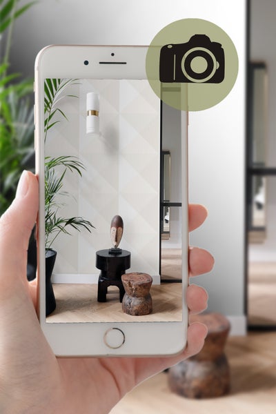 Aufnahme eines Interieurs mit geometrischer Tapete, einem kleinen Tisch mit Skulptur und einer Zimmerpflanze, aufgenommen mit einem Smartphone.