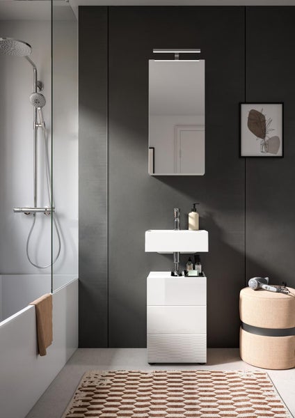 Modernes Badezimmer mit weißem Waschtischunterschrank, Waschbecken, Spiegel mit Beleuchtung und verchromtem Duschsystem über einer Badewanne.