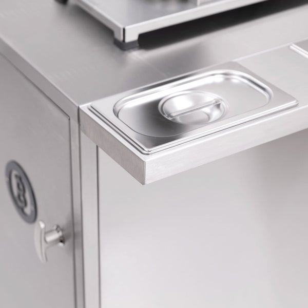 Detailaufnahme einer Edelstahl-Grillstation mit Behälter und Tür