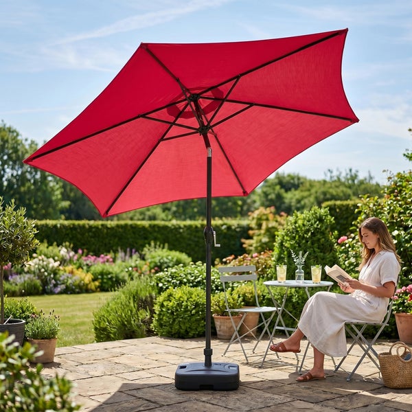 Großer roter rechteckiger Sonnenschirm auf einer Terrasse mit Sitzgruppe in einem hellen Garten.