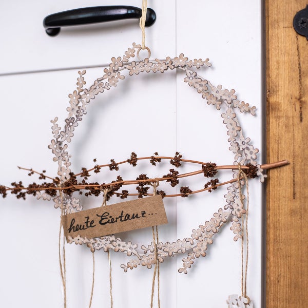 Dekorativer Kranz mit Blumenmuster, Zweig und Anhänger mit der Aufschrift 'heute Eiertanz'