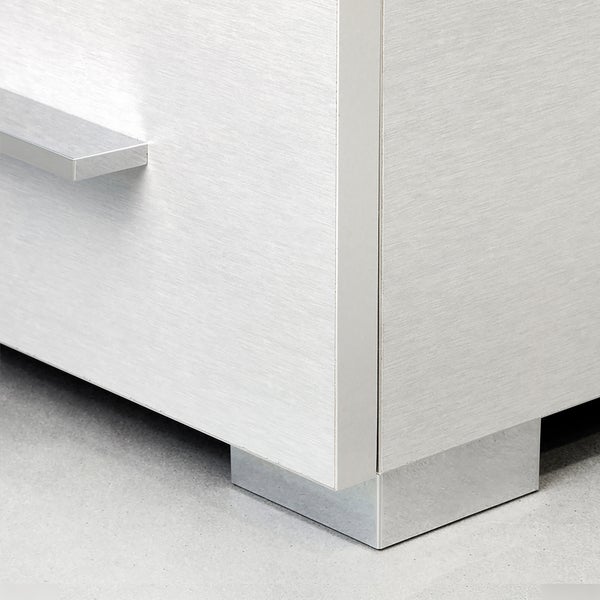 Detailansicht eines Möbelstücks mit glatter Oberfläche, Metallgriff und Metallfuß.