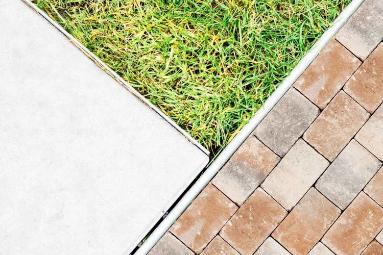 Ansicht von Betonplatten, Rasen und Pflastersteinen im Garten