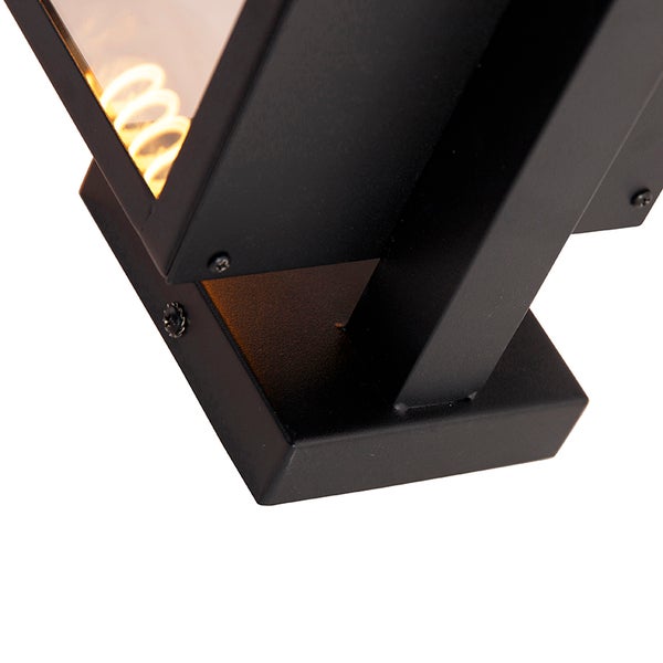 Nahaufnahme einer schwarzen Außenwandleuchte aus Metall mit Glaseinsatz und sichtbarem Leuchtmittel.