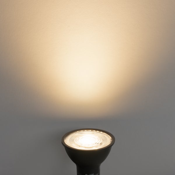 LED-Leuchtmittel GU10 mit warmweißem Lichtschein an einer Wand.