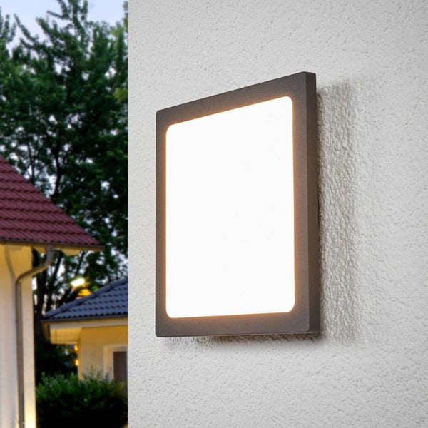 Quadratische LED-Außenwandleuchte in Anthrazit, montiert an einer strukturierten Fassade, eingeschaltet mit warmweißem Licht.