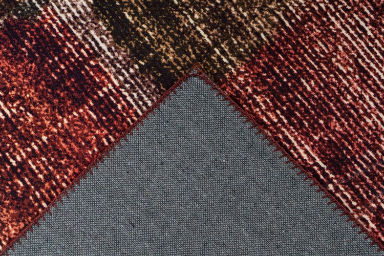 Detailansicht eines Teppichs mit abstraktem Muster und umgeklappter Ecke, die die graue Textilrückseite und die Kettelung zeigt.