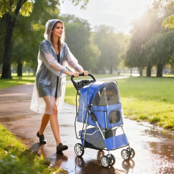 Frau in transparentem Regenmantel schiebt blauen Hundebuggy mit Regenschutz durch einen hellen Park bei Regen.
