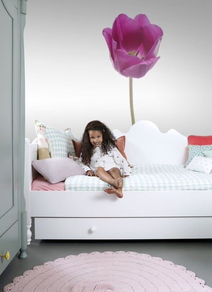 Kinderzimmer mit Mädchen auf Tagesbett, rundem Teppich und Blumentapete