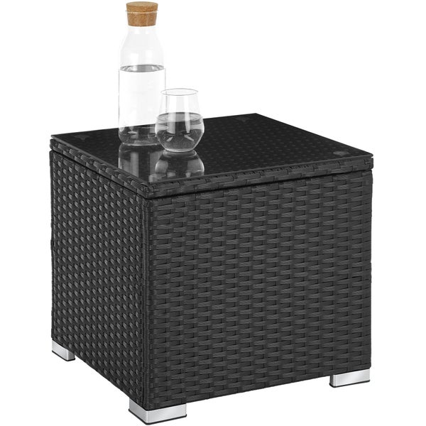 Würfelförmiger Beistelltisch aus anthrazitfarbenem Polyrattan mit einer dunklen Glasplatte, auf der eine Glaskaraffe und ein Wasserglas stehen.
