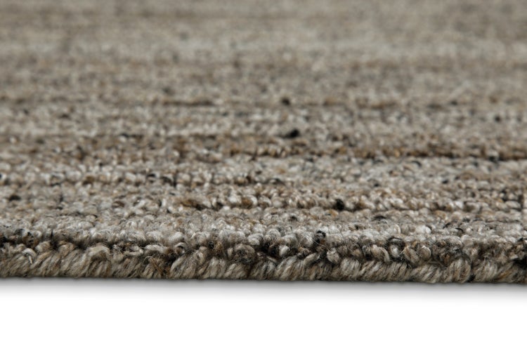 Nahaufnahme eines beige-braun melierten Teppichs mit strukturierter Oberfläche und Kante.