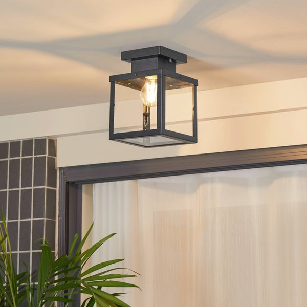 Hell gestalteter Außenbereich mit einer schwarzen quadratischen Deckenleuchte im Laternendesign, einer gefliesten Wand und einer Zimmerpflanze.