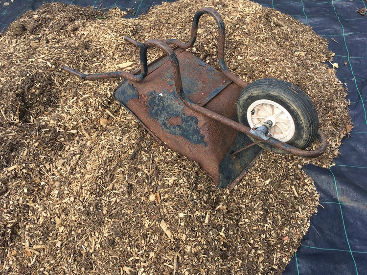 Eine Schubkarre liegt auf einer Mulchschicht.