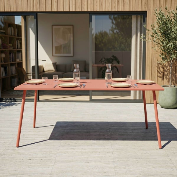 Moderner Gartentisch in Terracotta auf einer hellen Terrasse, eingedeckt für vier Personen vor einer Hausfassade mit Holzverkleidung.