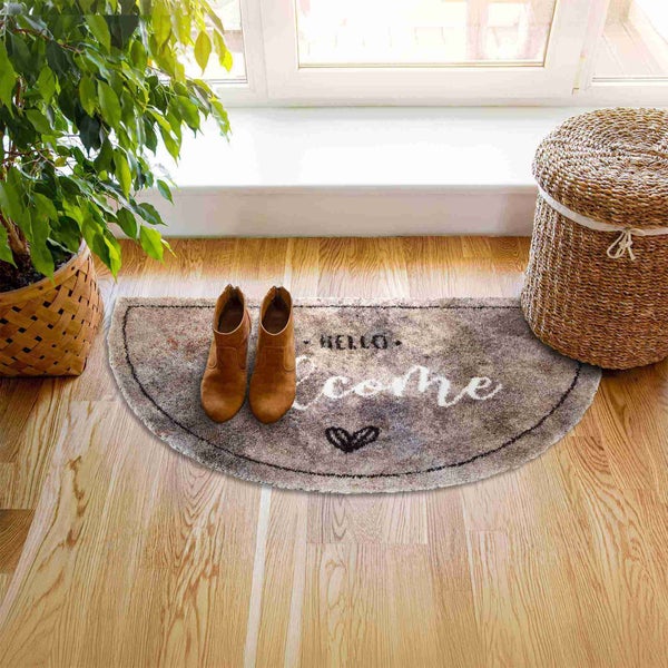 Dekorative Fußmatte mit Willkommensgruß, Schuhen, Topfpflanze und Wäschekorb im Eingangsbereich.