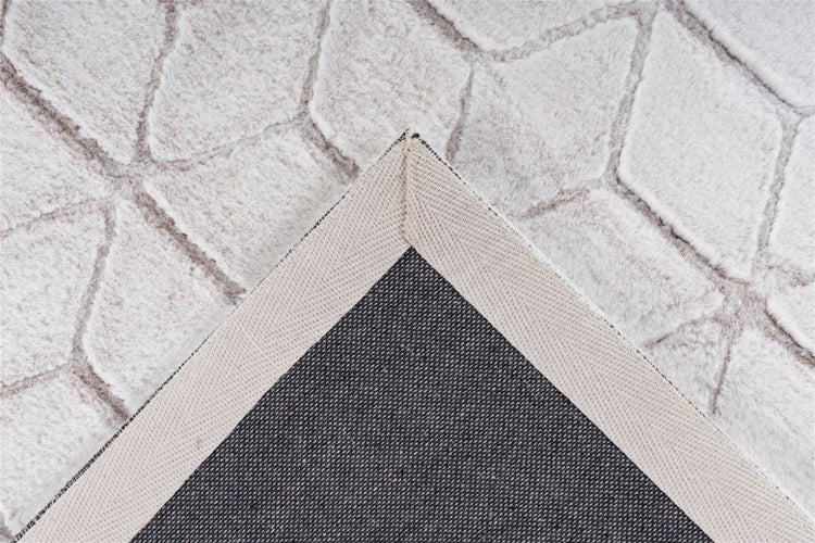 Detailansicht eines Hochflor-Teppichs mit geometrischem Muster und rutschfester Unterseite an einer umgeschlagenen Ecke.