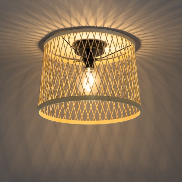 Deckenleuchte aus Bambus mit Gittermuster und eingeschaltetem Leuchtmittel, das ein Schattenmuster an die Decke wirft.