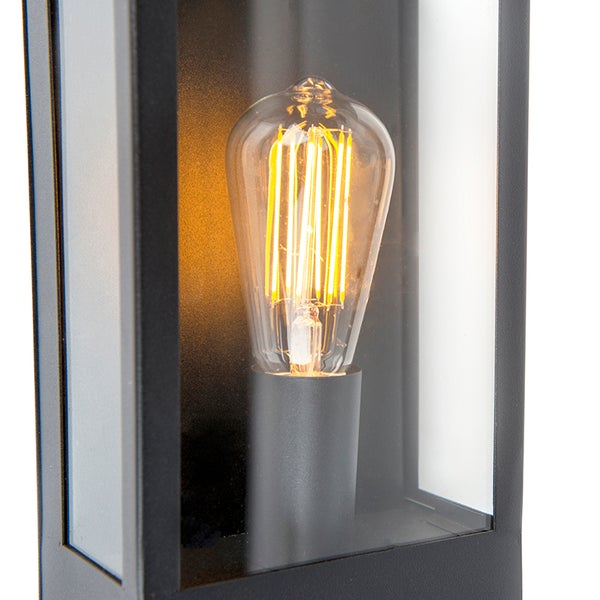 Nahaufnahme einer Außenwandleuchte mit schwarzem Metallrahmen, Glaseinsätzen und einem leuchtenden LED-Filament-Leuchtmittel im Vintage-Stil.