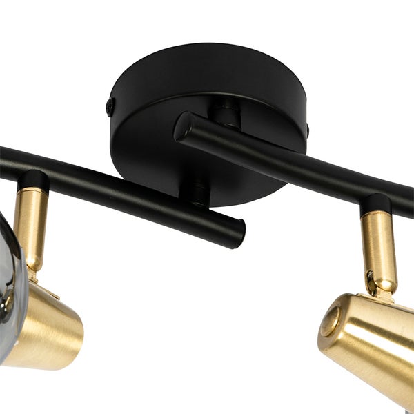 Deckenleuchte mit schwarzen Stangen und goldfarbenen Strahlern