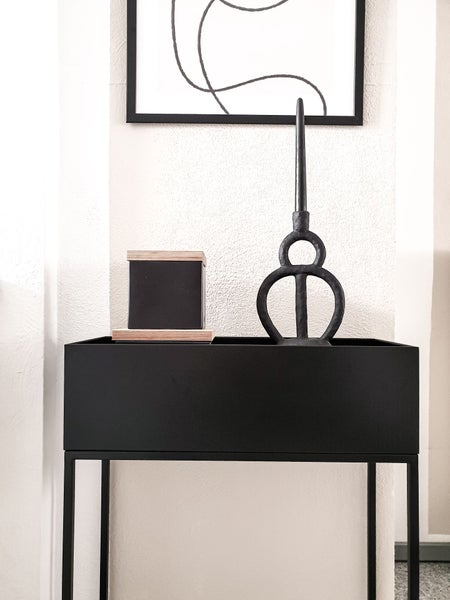 Schwarze Metall-Konsole in minimalistischem Design, dekoriert mit einer Aufbewahrungsbox und einer modernen Skulptur.