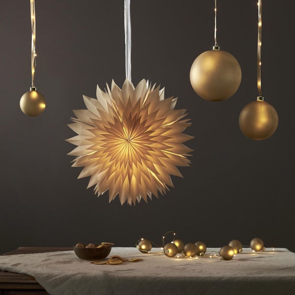 Dekoratives Arrangement mit Papierstern, Weihnachtskugeln und Lichterkette auf einem Tisch