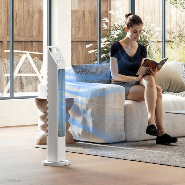 Weißer Turmventilator kühlt eine lesende Frau auf einem Sofa in einem hellen Wohnzimmer.