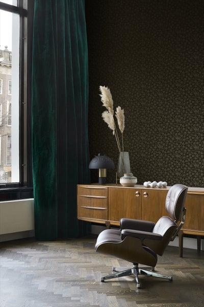 Wohnzimmer mit Sessel, Sideboard, Vorhang und gemusterter Tapete