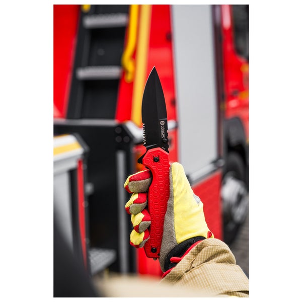 Dönges Rettungsmesser mit schwarzer Klinge und Wellenschliff, gehalten von einer Hand in Schutzhandschuhen vor einem Feuerwehrauto.