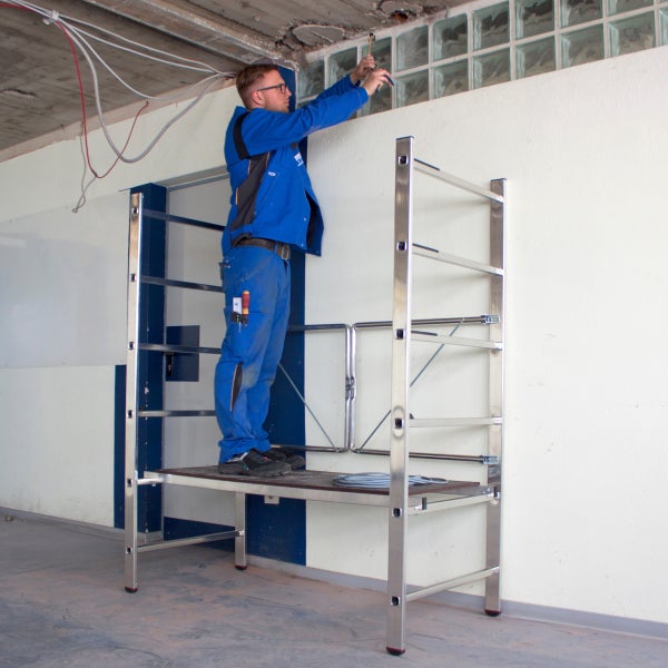 Elektriker auf einer Arbeitsbühne bei der Installation von elektrischen Leitungen an der Decke.