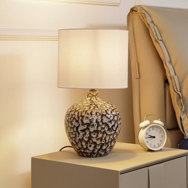 Dekorative Tischleuchte aus Keramik mit Lampenschirm auf einem Nachttisch