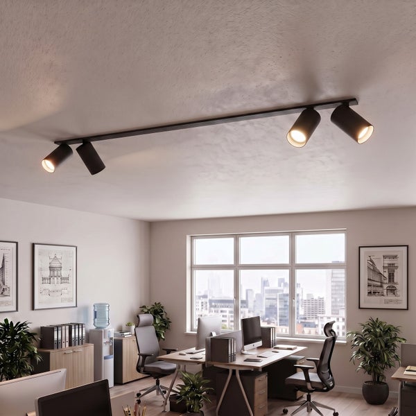 Moderne Deckenstrahlerschiene mit vier verstellbaren Leuchten in einem hellen, professionell eingerichteten Büro mit Schreibtischen und Pflanzen.