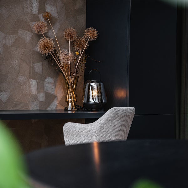 Dekorative Tischlampe neben einer Vase mit Trockenblumen auf einem Tisch