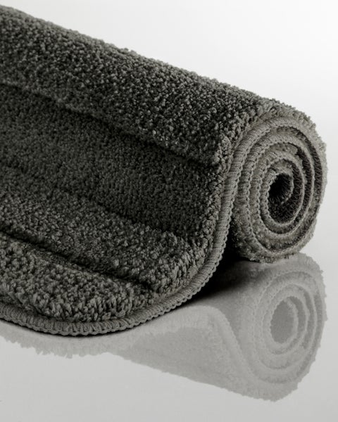 Graue, aufgerollte Badematte aus weichem Material mit strukturierter Oberfläche.