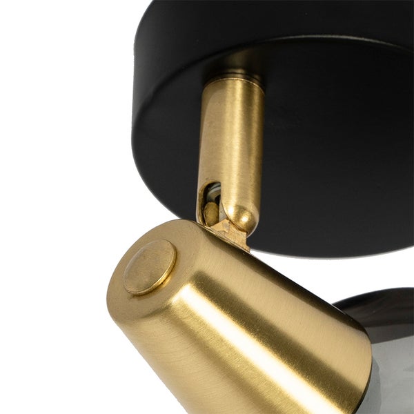 Detailansicht des verstellbaren Gelenks einer Leuchte in Messing-Optik mit schwarzer Basis.