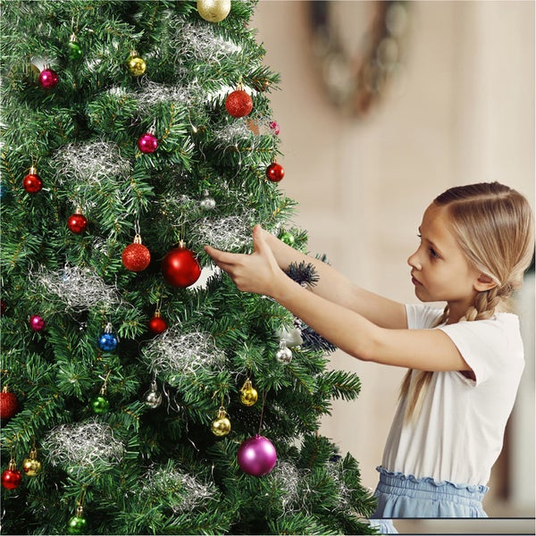 Mädchen schmückt einen Weihnachtsbaum mit Christbaumkugeln und Lametta
