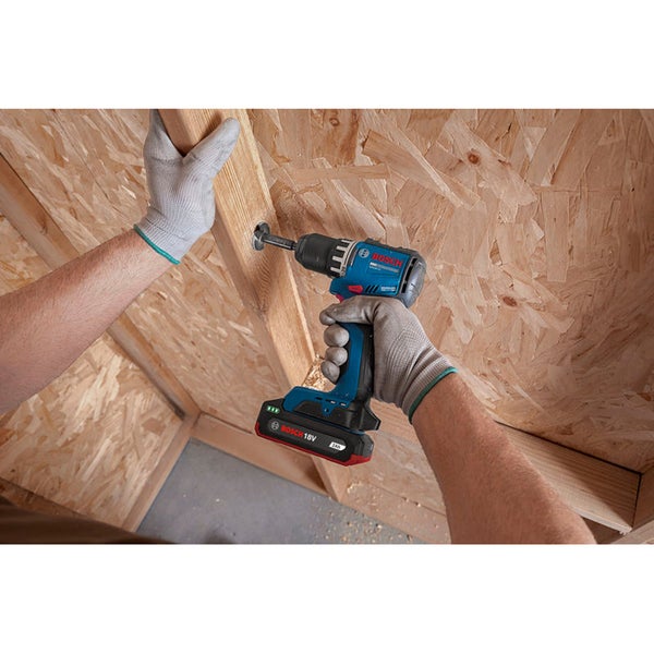 Person bohrt mit einem Bosch Akku Schrauber in eine Holzbalkenkonstruktion aus Grobspanplatten.