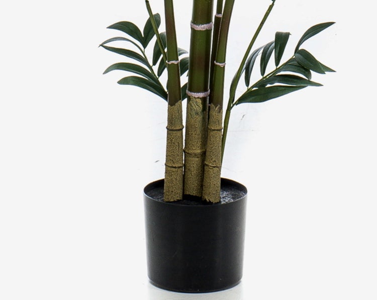 Künstliche Bambuspflanze im schwarzen Kunststofftopf mit grünen Halmen und Blättern.