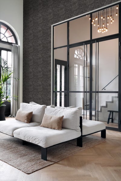 Heller Wohnraum mit Sofa, Teppich und Raumteiler mit Glaseinsätzen