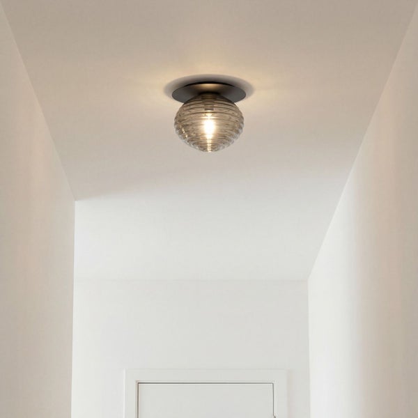 Runde Deckenleuchte mit geriffeltem Glasschirm montiert in einem hellen, schmalen Flur.