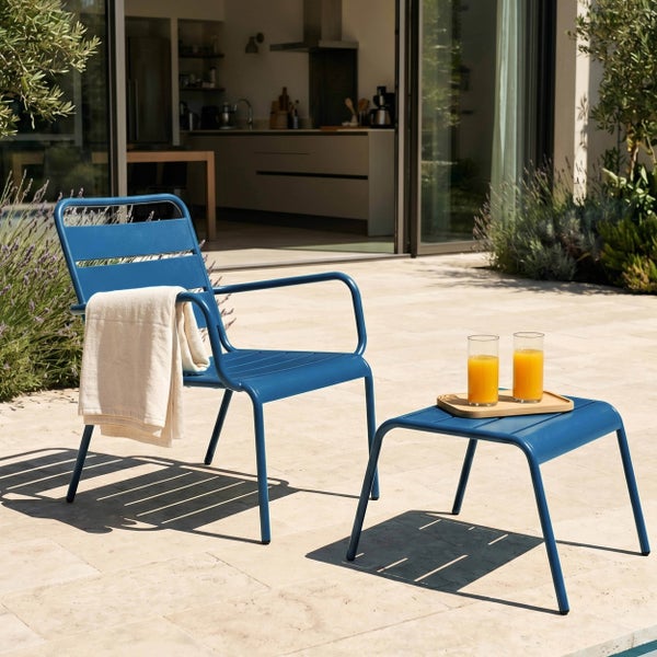 Garten-Armlehnstuhl und Beistelltisch aus Metall auf einer Terrasse vor einer modernen Wohnküche.