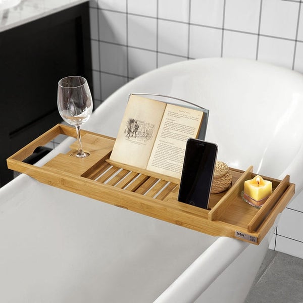 Badezimmer Szene mit Badewannenablage aus Holz mit Weinglas, Buch, Smartphone und Kerze.