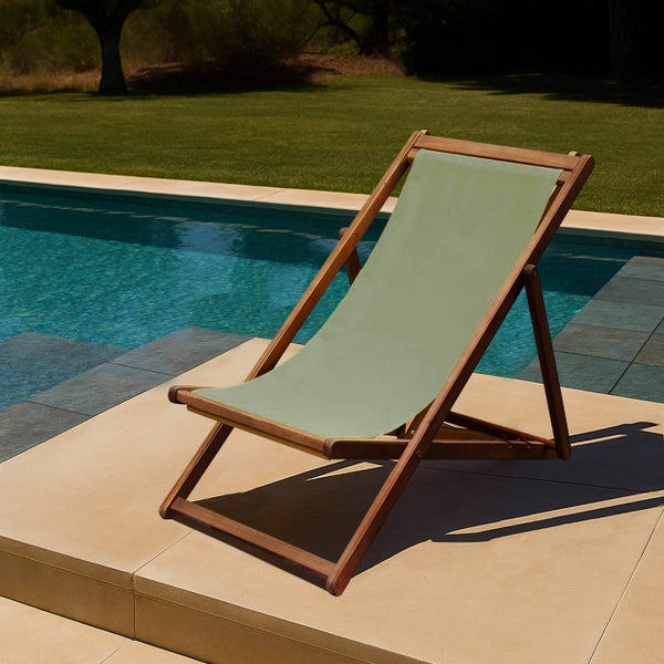 Klappbarer Liegestuhl aus Holz mit grünem Stoffbezug auf einer Terrasse neben einem Swimmingpool.