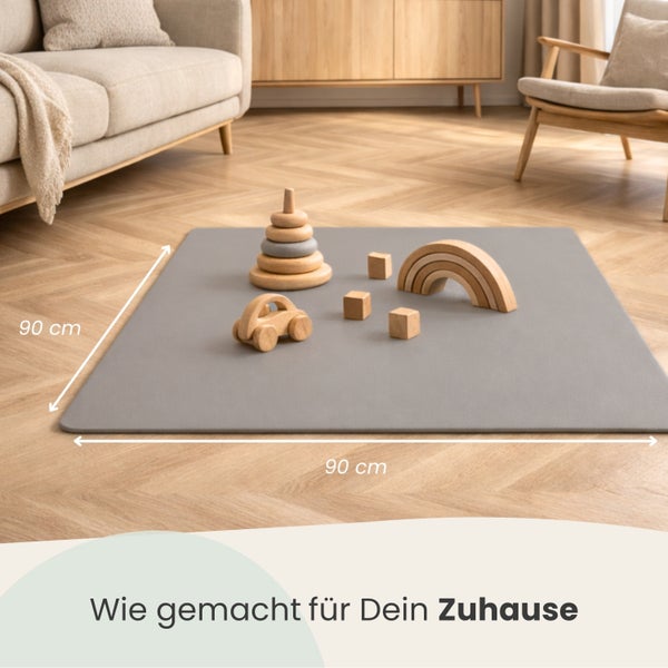 Quadratische Spielmatte in Grau auf Fischgrätparkett im Wohnzimmer, Maße 90 mal 90 Zentimeter, mit Holzspielzeug.