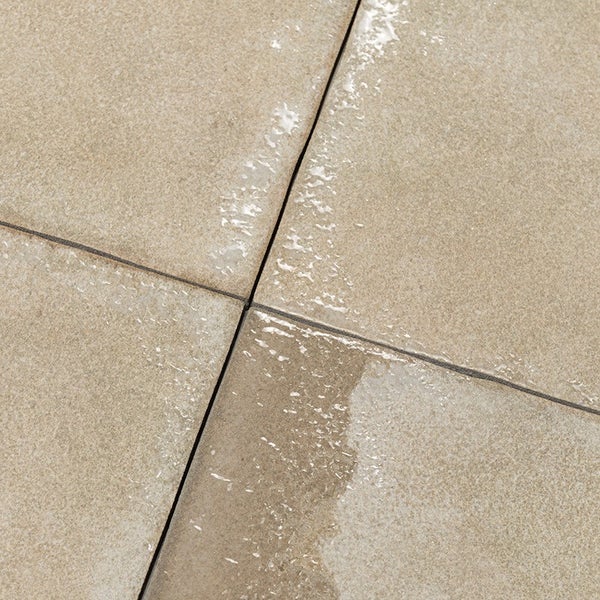 Quadratische Terrassenplatten aus Stein mit feiner Textur und feuchten Stellen in der Draufsicht.