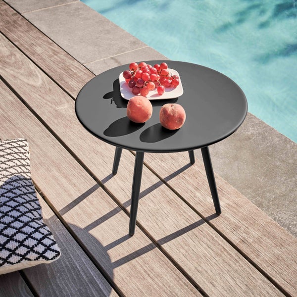 Runder schwarzer Gartenbeistelltisch auf einer Holzterrasse am Pool, dekoriert mit einer Schale Obst.