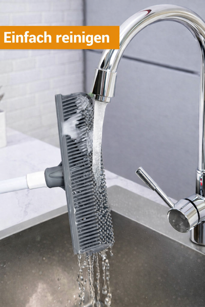 Eine Reinigungsbürste aus Silikon unter einem Wasserhahn mit fließendem Wasser.